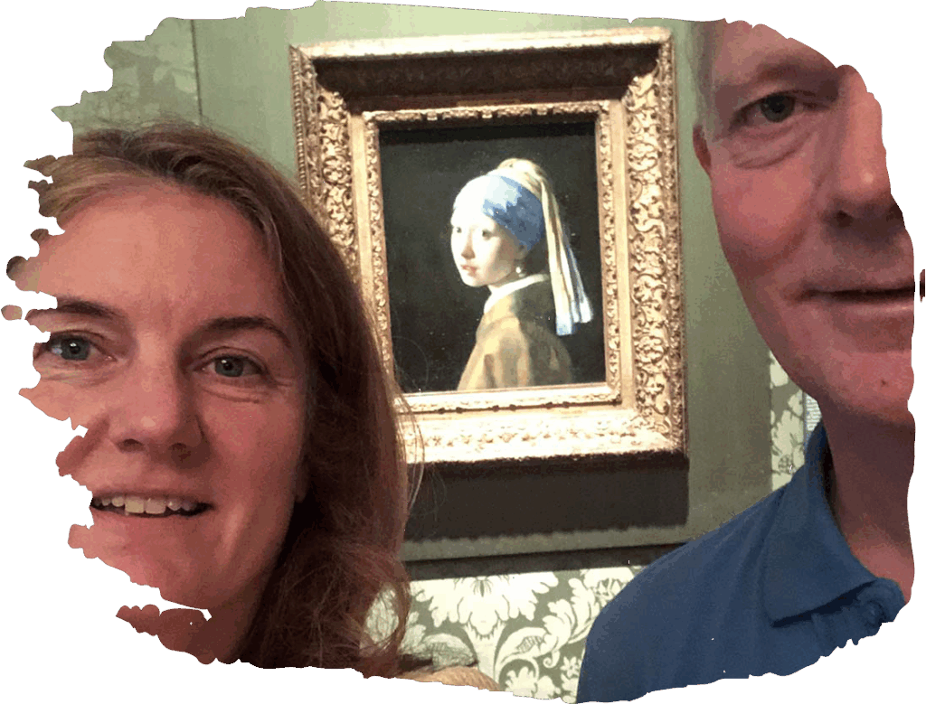 A couple taking a selfie in front of Vermeer's Girl with a Pearl Earring painting in a museum setting.