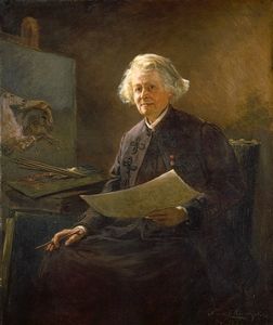 Elderly artist holding paper, seated with painting tools and artwork in background, dressed in dark clothing.