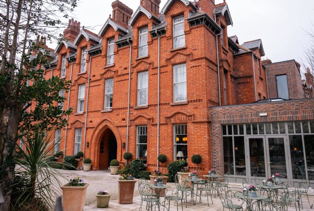 Charming red brick building with outdoor seating and lush greenery, ideal for a cozy and inviting atmosphere.